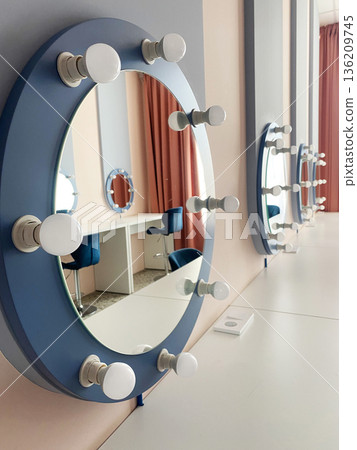 Elegant vanity mirrors with bright bulbs reflect stylish interior design, showcasing a modern beauty salon atmosphere with comfortable seating and soft lighting for a welcoming experience 136209745