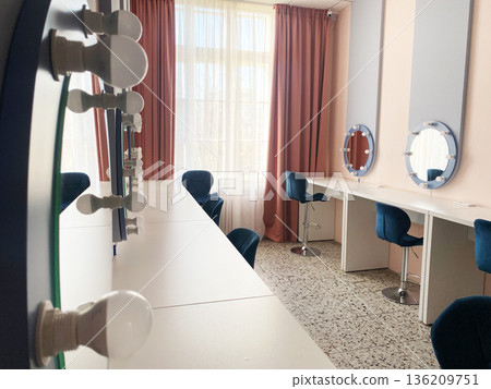 Modern beauty salon interior featuring elegant mirrors, stylish blue chairs, and bright natural light creating a welcoming atmosphere for clients and professionals in a chic environment 136209751