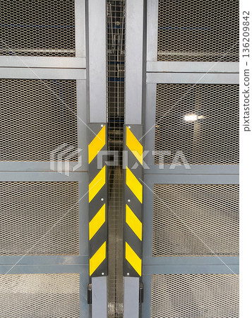 Industrial metal gate with mesh design, featuring bold yellow and black warning stripes, creating a secure and modern entrance to a facility, emphasizing safety and functionality Industrial metal gate with mesh design, featuring bold yellow and black warning stripes, creating a secure and modern entrance to a facility, emphasizing safety and functionality 136209842