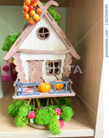 Colorful wooden toy house with vibrant details, surrounded by green moss and decorative mushrooms, creating a whimsical atmosphere for kindergarten play and imagination Colorful wooden toy house with vibrant details, surrounded by green moss and decorative mushrooms, creating a whimsical atmosphere for kindergarten play and imagination 136209844