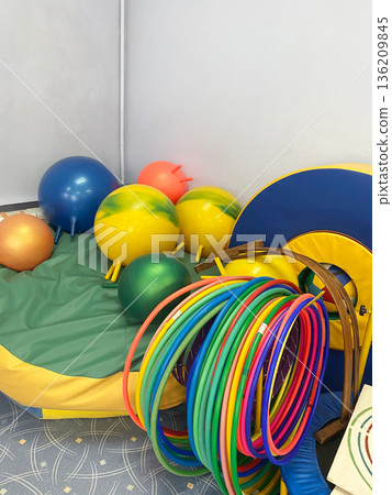 Colorful sports equipment including balls, hula hoops, and soft mats arranged in a kindergarten play area, promoting active play and physical development for young children Colorful sports equipment including balls, hula hoops, and soft mats arranged in a kindergarten play area, promoting active play and physical development for young children 136209845