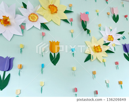 Colorful paper flowers and tulips are beautifully arranged on a light green wall, creating a vibrant and cheerful atmosphere for spring decoration and celebration 136209849