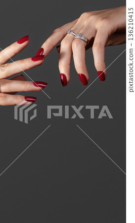 Beautiful glamour photo of elegant female hands with bright burgundy manicure on gray background. Long square nails with dark red gel polish. Luxury fashion style of brilliants jewelry rings Beautiful glamour photo of elegant female hands with bright burgundy manicure on gray background. Long square nails with dark red gel polish. Luxury fashion style of brilliants jewelry rings 136210415