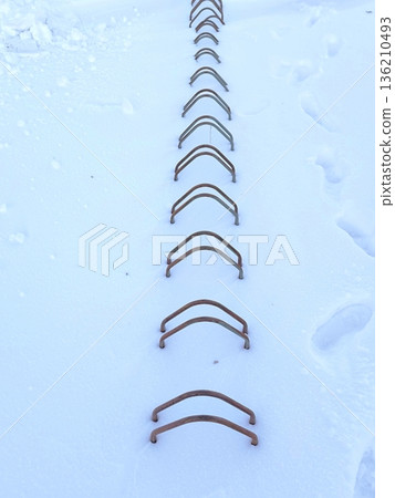 A row of metal bike racks covered in deep snow 136210493