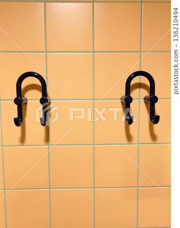 Two double blue plastic coat hooks on orange tiles Two double blue plastic coat hooks on orange tiles 136210494