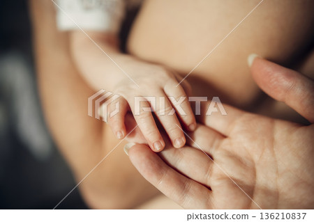 A baby's hand is being held by a woman's hand 136210837