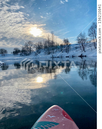 A person is paddling a surfboard on a lake A person is paddling a surfboard on a lake 136210841