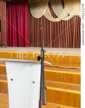 Retro-style school assembly hall featuring a podium and wooden stage, adorned with elegant drapery, creating a nostalgic atmosphere for educational events and gatherings 136211276