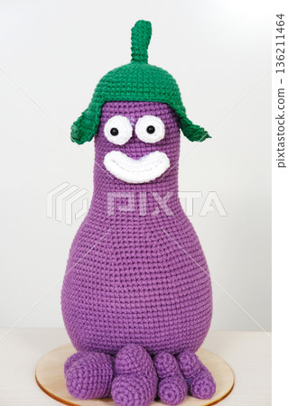 Unique handmade knitted toy in vibrant purple with green hat and white facial features, perfect for imaginative play and decorative purposes, featuring copy space for creative use 136211464