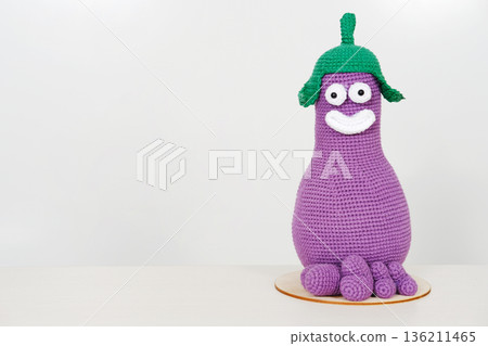 Unique knitted toy character in vibrant purple with green hat and cheerful expression, perfect for imaginative play and decorative purposes, featuring copy space for versatile use Unique knitted toy character in vibrant purple with green hat and cheerful expression, perfect for imaginative play and decorative purposes, featuring copy space for versatile use 136211465