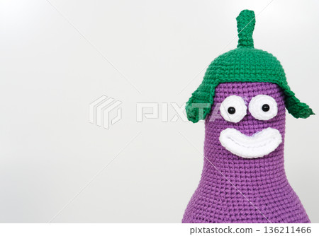 Unique handmade knitted toy with vibrant purple body and green hat, featuring a cheerful face, perfect for imaginative play and decoration with copy space 136211466