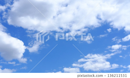 Bright blue sky with fluffy white clouds scattered across, creating a serene atmosphere, ideal for backgrounds or nature-themed projects, conveying tranquility and openness Bright blue sky with fluffy white clouds scattered across, creating a serene atmosphere, ideal for backgrounds or nature-themed projects, conveying tranquility and openness 136211531