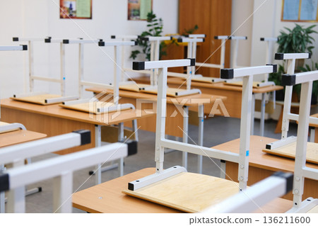 Classroom with raised chairs and empty desks, showcasing a tidy educational environment, symbolizing the end of the school day and the concept of school education Classroom with raised chairs and empty desks, showcasing a tidy educational environment, symbolizing the end of the school day and the concept of school education 136211600