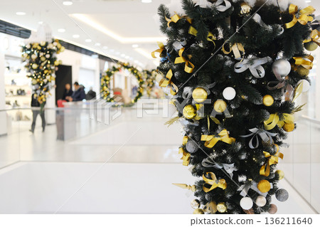 Christmas decorations featuring vibrant ornaments and ribbons adorn a shopping center, creating a festive atmosphere with holiday spirit and cheer throughout the public space 136211640