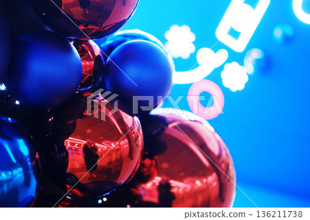 Colorful arrangement of glossy red and blue spheres against a vibrant blue background, creating a festive atmosphere with reflections and playful lighting effects 136211738