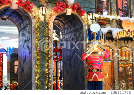 Colorful Christmas decor featuring a toy soldier statue, garlands, and festive lights in a stylish shopping center, creating a joyful holiday atmosphere for shoppers Colorful Christmas decor featuring a toy soldier statue, garlands, and festive lights in a stylish shopping center, creating a joyful holiday atmosphere for shoppers 136211796
