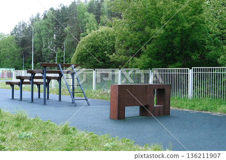 Military training ground featuring obstacle course with climbing structures and benches, designed for personnel development and tactical exercises in a natural outdoor environment Military training ground featuring obstacle course with climbing structures and benches, designed for personnel development and tactical exercises in a natural outdoor environment 136211907