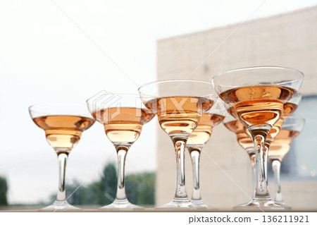 Elegant champagne glasses filled with sparkling rose wine are arranged in a row, showcasing the delicate hues and reflections, perfect for celebrations and toasting moments 136211921