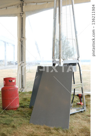 Heat gun positioned next to a propane gas cylinder, showcasing the setup for heating tasks in an outdoor environment with a focus on safety and functionality Heat gun positioned next to a propane gas cylinder, showcasing the setup for heating tasks in an outdoor environment with a focus on safety and functionality 136211984