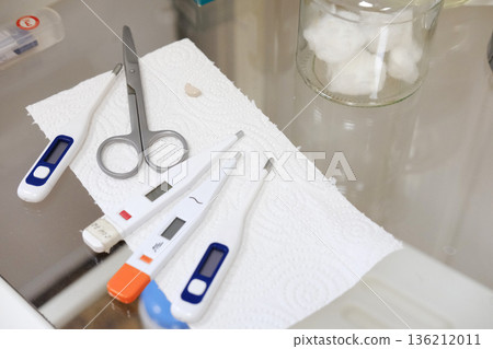 Medical instruments including thermometers, scissors, and cotton balls arranged neatly on a clean surface, showcasing essential tools for healthcare and clinical settings Medical instruments including thermometers, scissors, and cotton balls arranged neatly on a clean surface, showcasing essential tools for healthcare and clinical settings 136212011