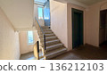 Residential apartment building stairwell with concrete stairs, metal railings and windows 136212103