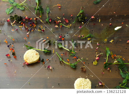 Leftover food scattered on a wooden table, featuring dirty dishes, remnants of a meal, and colorful edible flowers, creating a messy yet artistic culinary scene Leftover food scattered on a wooden table, featuring dirty dishes, remnants of a meal, and colorful edible flowers, creating a messy yet artistic culinary scene 136212128