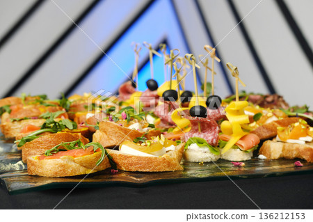 Colorful assortment of gourmet appetizers on a glass platter, featuring fresh ingredients, vibrant garnishes, and elegant presentation for a festive event or gathering Colorful assortment of gourmet appetizers on a glass platter, featuring fresh ingredients, vibrant garnishes, and elegant presentation for a festive event or gathering 136212153