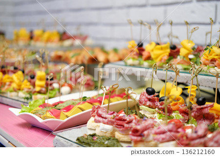 Colorful assortment of gourmet appetizers displayed elegantly on platters, featuring fresh fruits, meats, and garnishes, perfect for catering events and celebrations Colorful assortment of gourmet appetizers displayed elegantly on platters, featuring fresh fruits, meats, and garnishes, perfect for catering events and celebrations 136212160