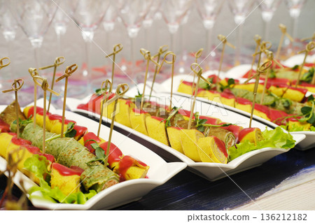 Colorful assortment of gourmet appetizers displayed elegantly on white platters, garnished with fresh herbs, showcasing culinary artistry and vibrant presentation for event catering Colorful assortment of gourmet appetizers displayed elegantly on white platters, garnished with fresh herbs, showcasing culinary artistry and vibrant presentation for event catering 136212182
