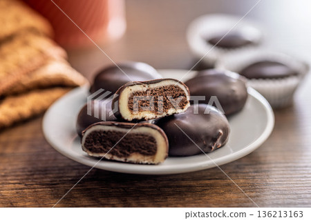 Dark chocolate truffles in the shape of coffee beans on plate on wooden table. Dark chocolate truffles in the shape of coffee beans on plate on wooden table. 136213163
