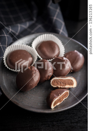 Dark chocolate truffles in the shape of coffee beans on plate on black table. Dark chocolate truffles in the shape of coffee beans on plate on black table. 136213165