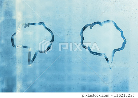 Hand drawn two blue speech bubble shape cloud for text on muddy cold glass wet window at home, copy space 136213255
