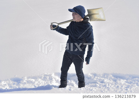一位居住在降雪量很大的農村地區的老人正在清理積雪。 一位居住在降雪量很大的農村地區的老人正在清理積雪。 136213879