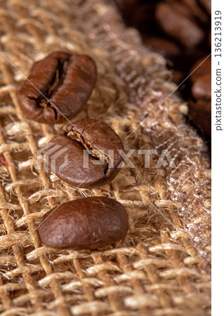 Close-up of coffee beans artfully arranged on a rustic burlap napkin 136213919