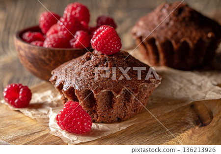 Freshly baked chocolate muffins artfully adorned with luscious ripe raspberries 136213926