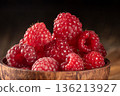 Close-up of a rustic wooden cup filled with fresh raspberries on a wooden table 136213927