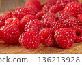 Close-up of fresh ripe raspberries scattered on a rustic table surface 136213928