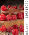 Delicious chocolate muffins elegantly decorated with fresh ripe raspberries 136213929