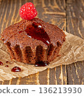 Delicious chocolate muffin topped with fresh raspberries close-up view 136213930