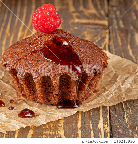 Delicious chocolate muffin topped with fresh raspberries close-up view Delicious chocolate muffin topped with fresh raspberries close-up view 136213930