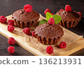 Freshly baked muffins surrounded by juicy raspberries on a black kitchen table 136213931