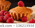 Lemon muffins surrounded by juicy raspberries on a cozy kitchen table scene 136213938