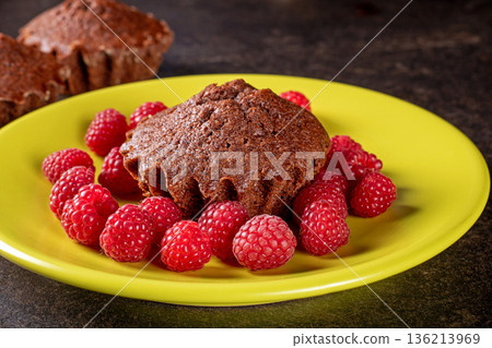Delicious muffin on a bright green plate surrounded by fresh raspberries Delicious muffin on a bright green plate surrounded by fresh raspberries 136213969