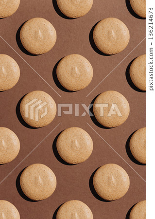 Seamless pattern of beige macarons with hard shadows on brown background 136214673