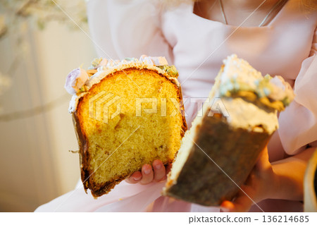 Child hands holding sliced Easter kulich bread with icing in soft spring light 136214685