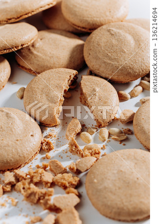 Broken peanut macarons with crumbs and nuts on white background, close up 136214694