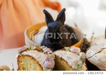 Black baby bunny with sliced Easter cake and festive spring dessert table 136214715