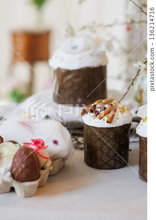 White bunny with Easter cakes and chocolate eggs, cozy spring still life, soft bokeh 136214716