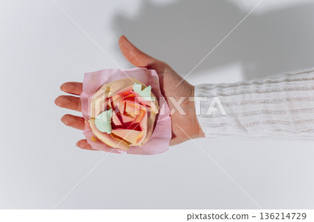 Hand holding white meringue rose on pink paper, minimal studio background Hand holding white meringue rose on pink paper, minimal studio background 136214729
