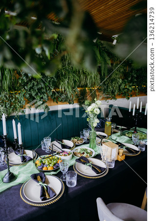 Elegant banquet table with green decor and lemonade pitcher in bright restaurant 136214739